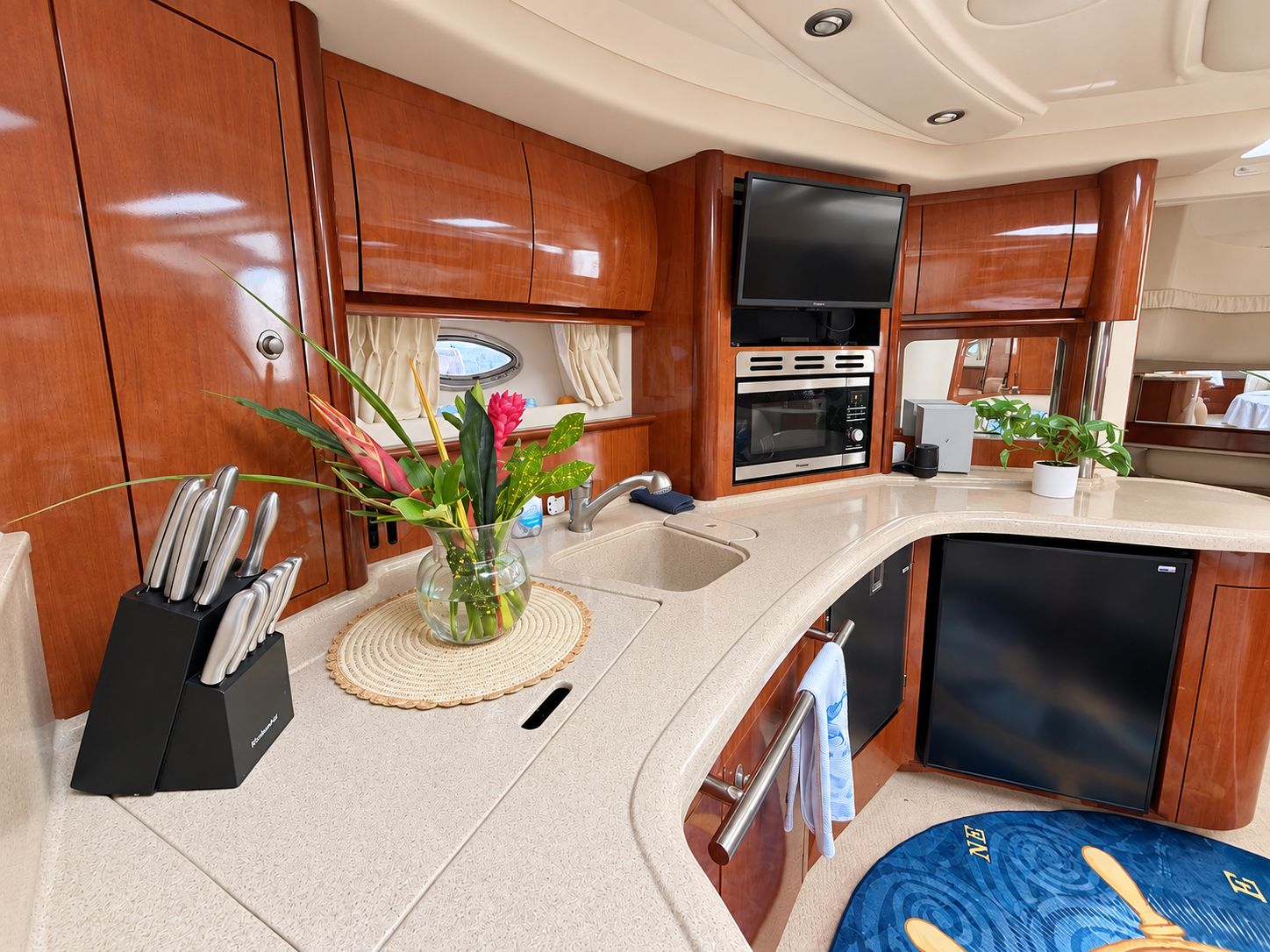 A compact kitchen with wooden cabinets, a sink, a microwave, and a small refrigerator.