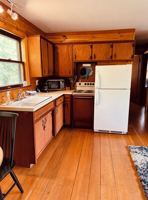 A kitchen with wooden cabinets, a white refrigerator, a stove, and a microwave. - Glidden Cottage -Beach Access! (Sturgeon Bay)