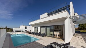 A modern house with a swimming pool, outdoor seating, and a covered patio.