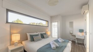 A modern hotel room with a large bed, bedside lamps, a desk, and a view of the outdoors.