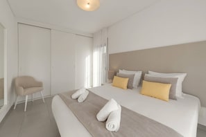 Habitació d'hotel moderna amb un llit gran, una cadira i vista exterior.