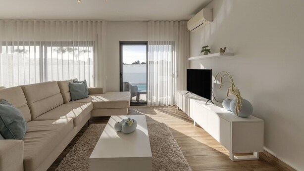 A modern living room with a sofa, coffee table, TV, and decorative items.
