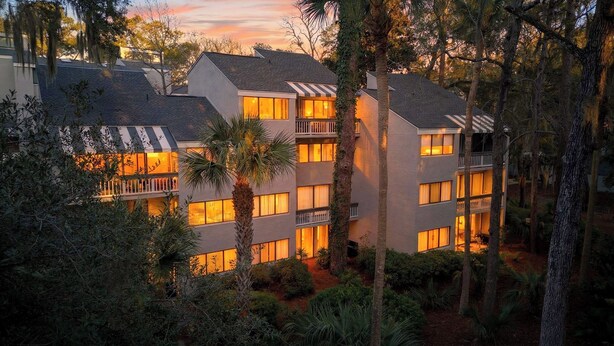 A multi-story hotel with balconies, surrounded by trees and vegetation. - Treetops 4904 by Avantstay Hilton Head Condo + Balcony + Shared Pool + Tennis Court + Near Beach and Dining (Hilton Head Island)