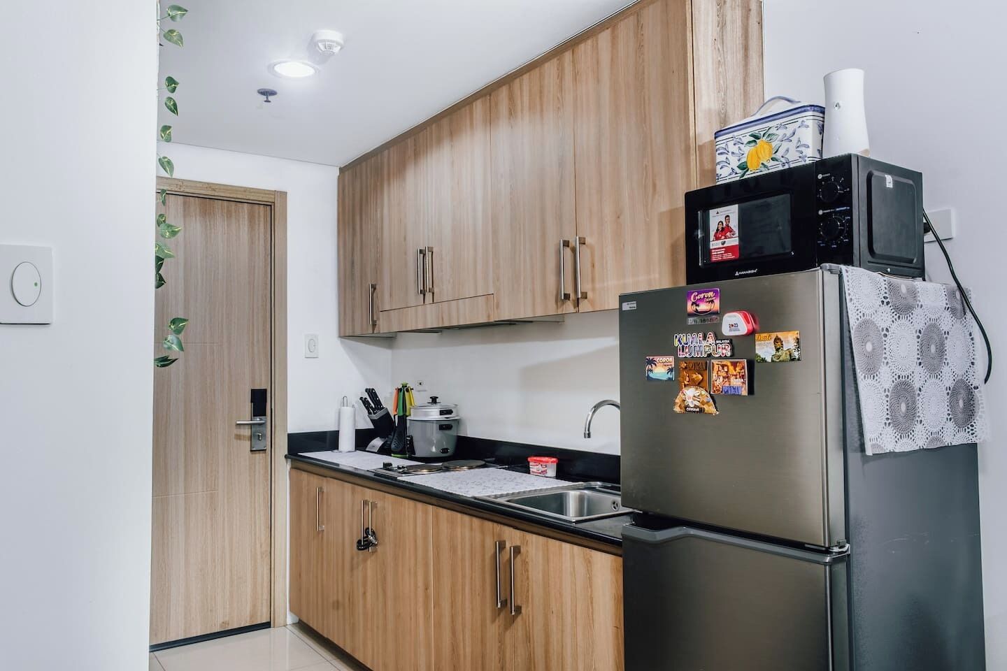 Una cocina moderna con armarios de madera, un refrigerador de acero inoxidable y un microondas.
