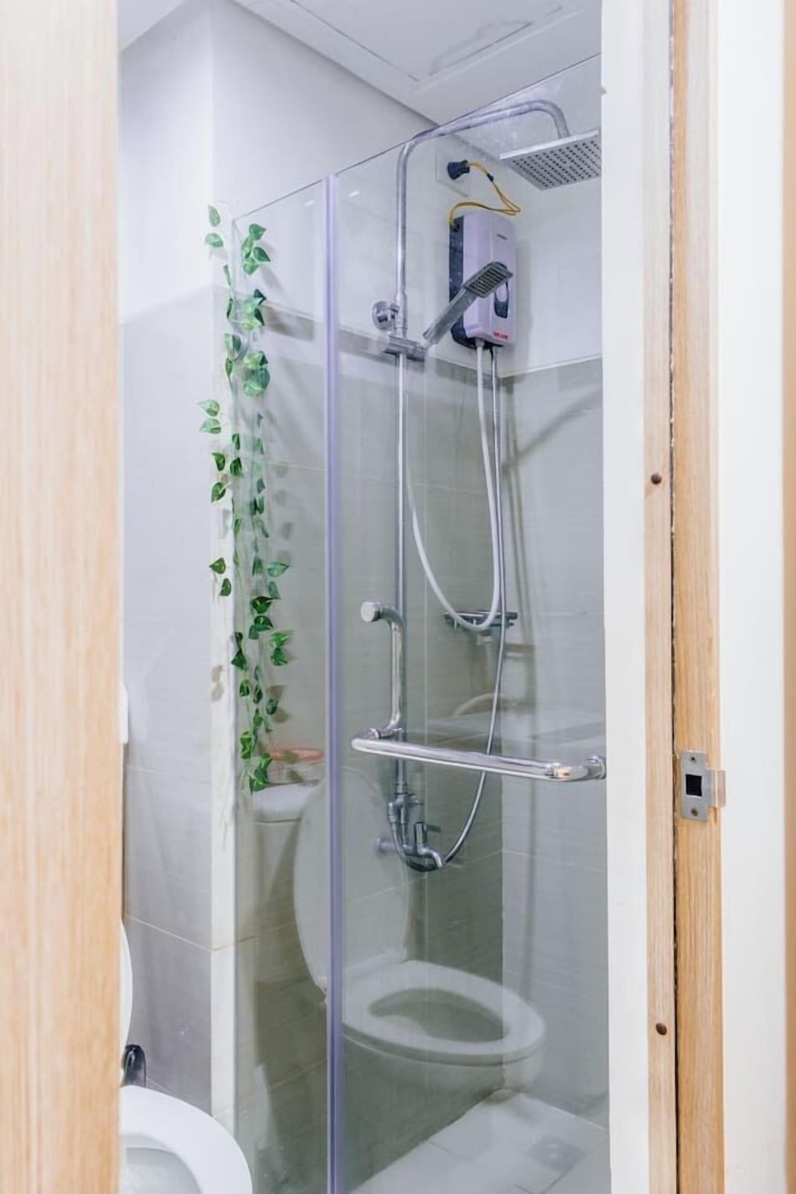 Een douchecabine met glazen wanden, een handdouche en een wandmengkraan.