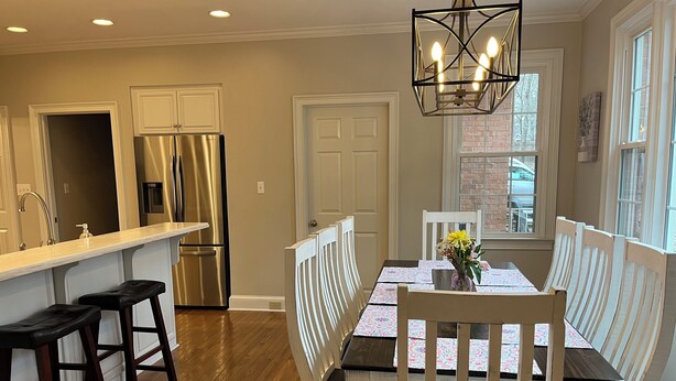 A kitchen with a stainless steel refrigerator, wooden bar stools, and a dining table with white chairs. - Masters Rental: 4BR/3.5 Bath, 4.7 miles to course (Augusta)
