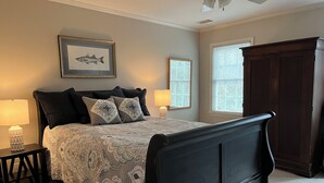 A bedroom with a bed, two bedside lamps, a framed fish picture, a window with blinds, and a dark wooden wardrobe. - Masters Rental: 4BR/3.5 Bath, 4.7 miles to course (Augusta)