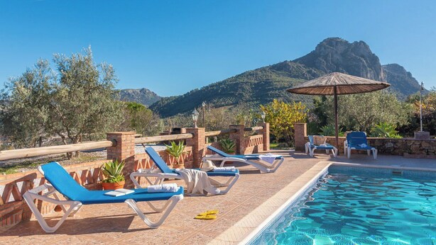 A poolside area with lounge chairs and a view of mountains.