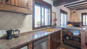 A kitchen with granite countertops, a double sink, wooden cabinets, and a stone backsplash.
