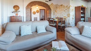 A living room with two sofas, a coffee table, and a dining area with a table and chairs.