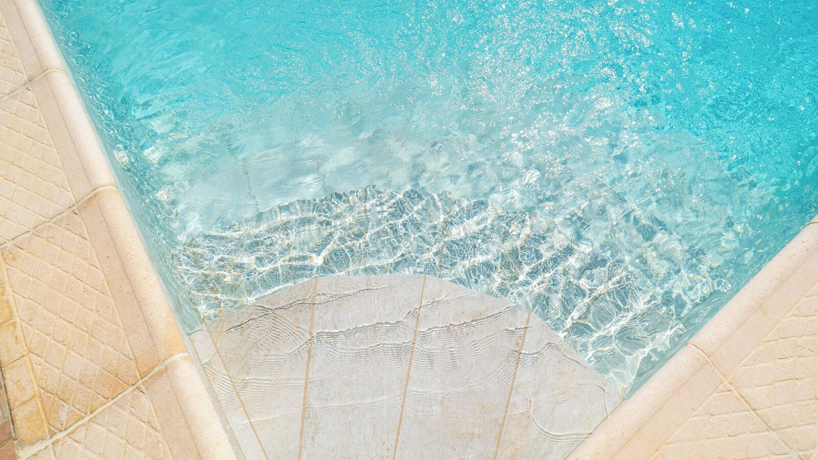 A clear view of a swimming pool with visible water patterns and a tiled edge.