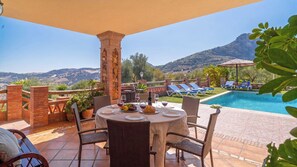 An outdoor dining area with a pool and mountain views.