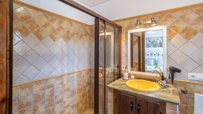 A bathroom with a yellow sink, a glass shower enclosure, and a large mirror.