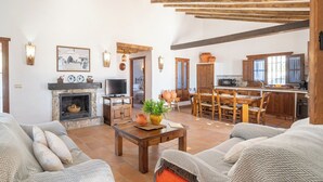 Ein geräumiges Wohnzimmer mit Kamin, Fernseher und Essbereich mit Holztischen und -stühlen.