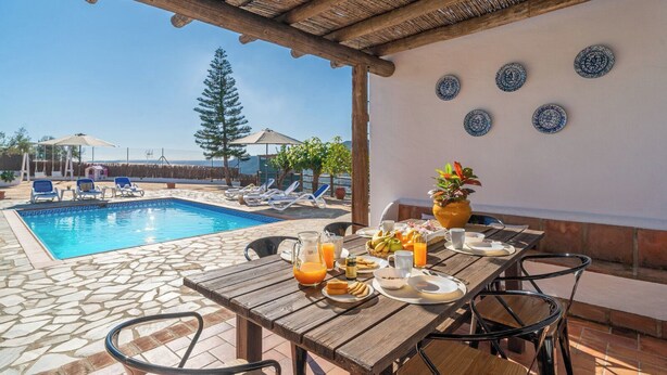 Ein Essbereich am Pool mit einem Tisch, der für das Frühstück gedeckt ist, mit Blick auf ein Schwimmbecken.