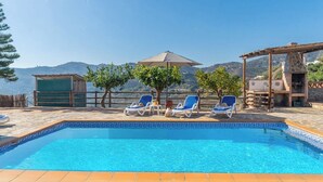 Ein Swimmingpool mit blauen Fliesen, umgeben von Liegestühlen und einer Pergola.