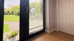 A room with a sliding glass door leading to a garden, a white door, and a wooden floor. - Comfortable unique space close to Warrenpoint  (Warrenpoint)