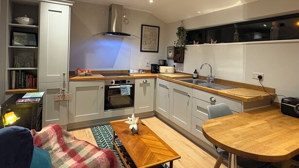 A modern kitchen with white cabinets, a built-in oven, and a wooden dining table. - Comfortable unique space close to Warrenpoint  (Warrenpoint)