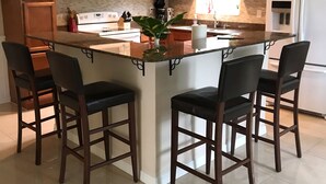 Eine moderne Küche mit Holzausstattung, einer zentralen Kochinsel mit Barhocker, einer Mikrowelle und einem Kühlschrank.