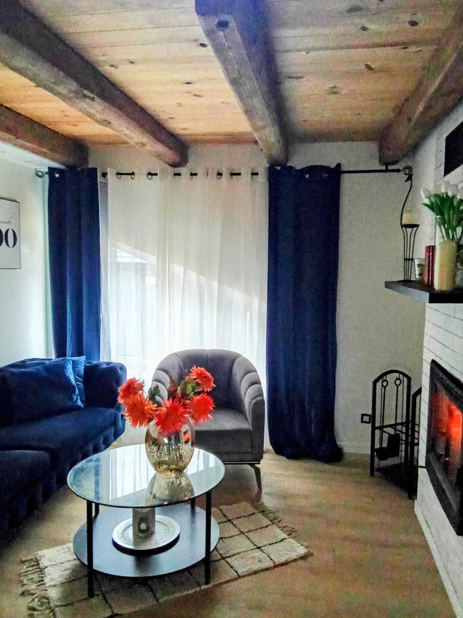 Ett vardagsrum med en soffa, en fåtölj och ett runt bord med en vas med blommor.