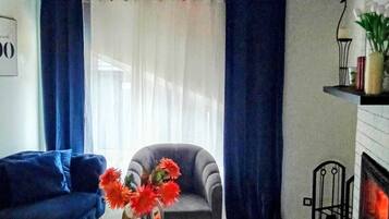Ett vardagsrum med en soffa, en fåtölj och ett runt bord med en vas med blommor.