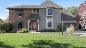 A two-story house with a brick facade, a red front door, and a grey roof. - Marvelous 4-bedroom house with Pool in lovely Lenexa World Cup Ready (Lenexa)