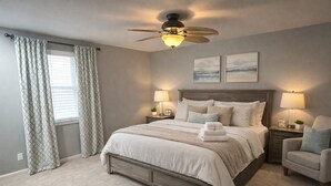 A bedroom with a bed, nightstands, a chair, a ceiling fan, and two wall-mounted lamps. - Marvelous 4-bedroom house with Pool in lovely Lenexa World Cup Ready (Lenexa)
