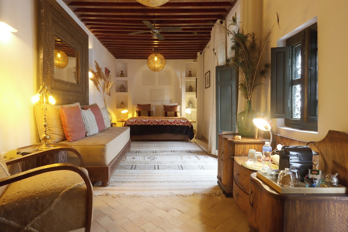 A cozy room with a bed, a desk, a mirror, and a ceiling fan.