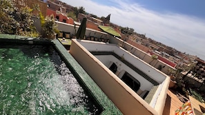 Ein Pool auf dem Dach mit klarem Wasser, einer gefliesten Liegefläche und Blick auf die Stadtlandschaft im Hintergrund.