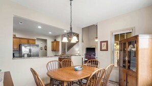 A dining area with a wooden table and chairs, a chandelier, and a wooden cabinet. - The Charming Retreat For 6! (Branson West)