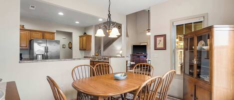 A dining area with a wooden table and chairs, a chandelier, and a wooden cabinet.