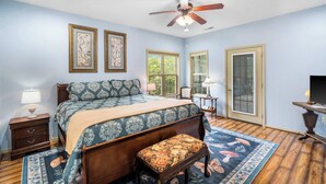 A bedroom with a bed, a bench, a ceiling fan, and framed artwork on the wall. - The Charming Retreat For 6! (Branson West)