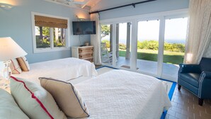 A bedroom with two beds, a TV, and a view of the outdoors. - Yellowbird Villa, Pool, Ocean Views, 6 bed, Luxury (St. Thomas)