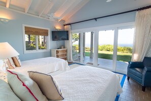 A bedroom with two beds, a TV, and a view of the outdoors. - Yellowbird Villa, Pool, Ocean Views, 6 bed, Luxury (St. Thomas)