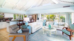 A spacious living area with a high ceiling, a kitchen with white cabinets, and a dining area with a table and chairs. - Yellowbird Villa, Pool, Ocean Views, 6 bed, Luxury (St. Thomas)