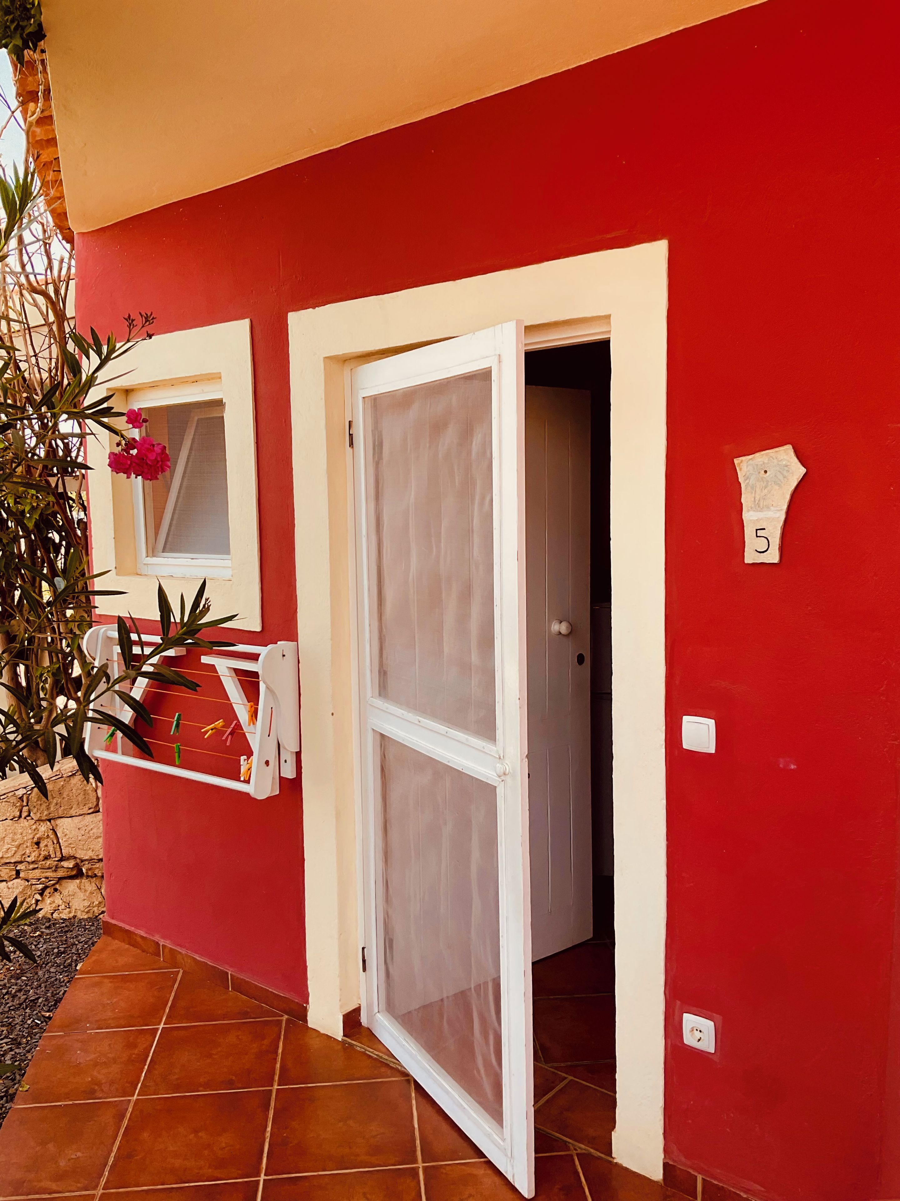A red building with a white door and a window with a white frame.