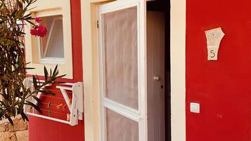 A red building with a white door and a window with a white frame.