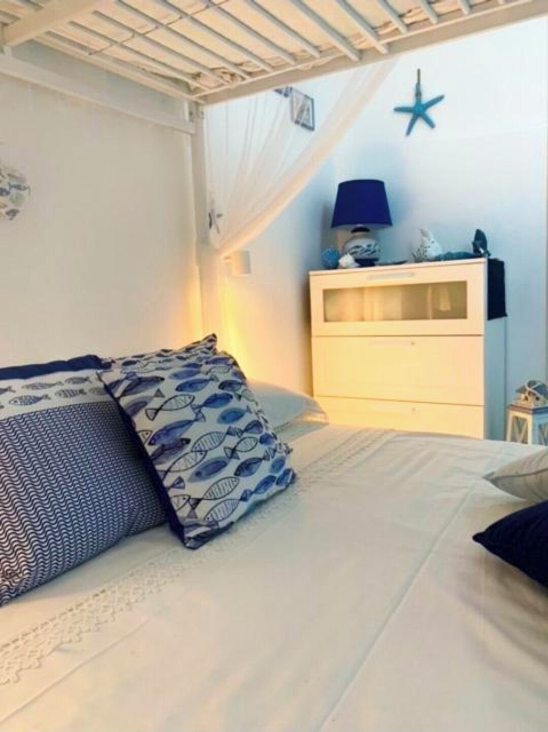 Una camera da letto con un letto, un comodino, una lampada e una decorazione a forma di stella sul muro.