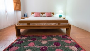 A bed with a wooden frame, a patterned rug, and a bedside lamp. - Sardinia Casa di Nonna Ida 7 rooms + garden+BBQ (Villaputzu)