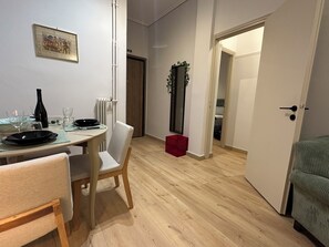 Ein Essbereich mit einem Tisch für zwei Personen, einem Stuhl, einer roten Aufbewahrungsbox und einem Spiegel an der Wand.