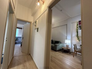 Ein Flur, der in einen Wohnbereich mit einer Couch, einem kleinen Tisch und einer Lampe führt.