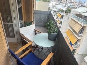 Ein Balkon mit Tisch, Stühlen und einem Blumentopf.