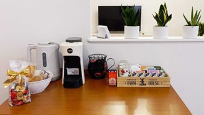 Eine Kaffeemaschine, eine Snackauswahl, eine Tasse, eine Schokoladentafel und Topfpflanzen auf einer Theke.