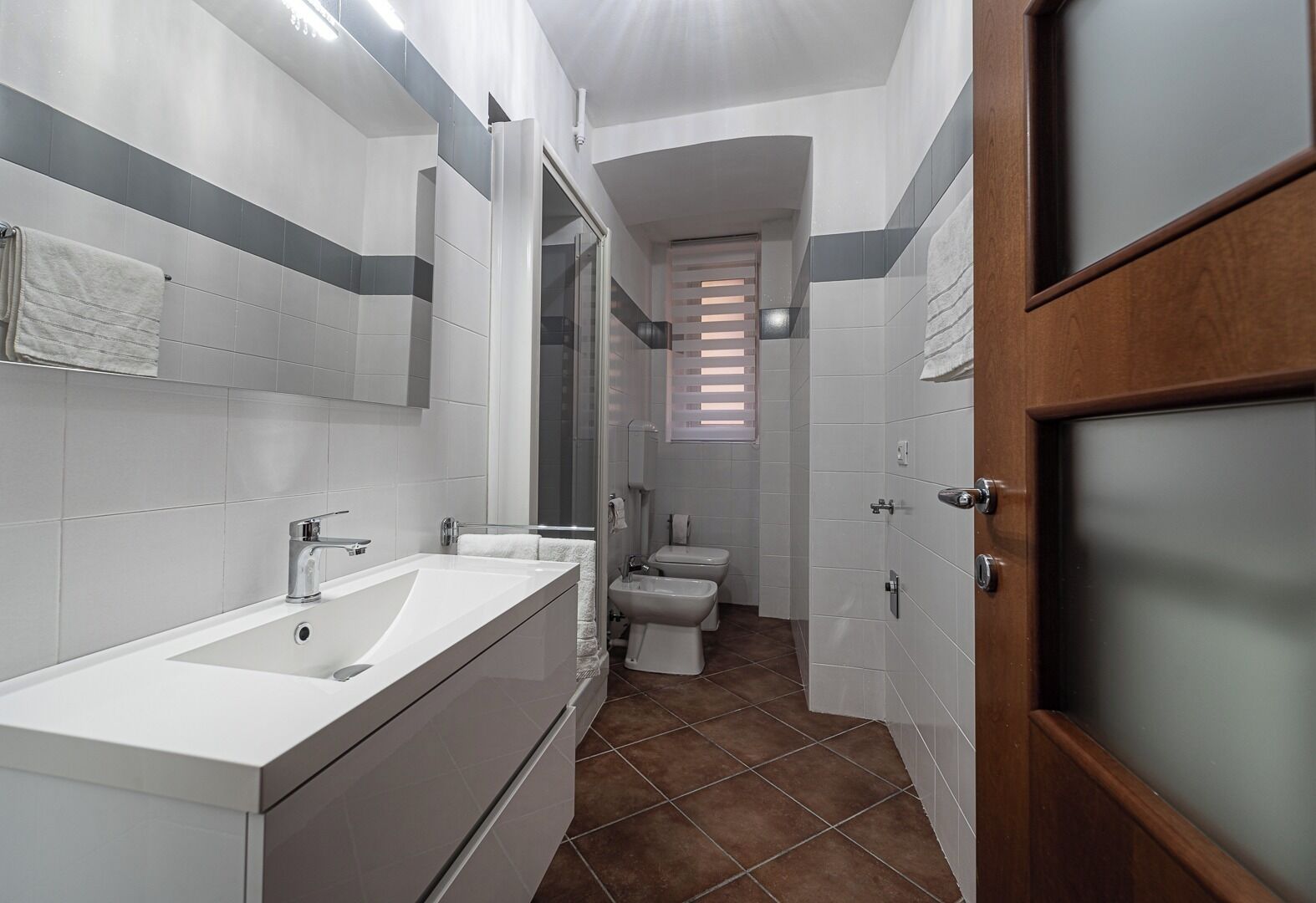 Een moderne badkamer met een groot wastafel, spiegel en toilet.