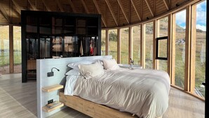 A bedroom with a large bed, wooden beams, and a view of the outdoors.