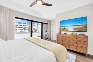 Ein Schlafzimmer mit einem großen Bett, einer Holzkommode, einem Stuhl und einem Bild mit einer Strandansicht.