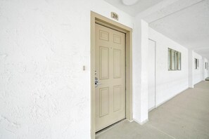 Ein Flur mit einer beigen Tür, auf der die Zahl 209 angebracht ist, und einem Fenster mit Messinggriffen.