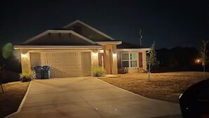 Ein Wohnhaus bei Nacht mit Garage, Auffahrt und kleinem Rasen.