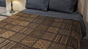 Ein Bett mit einem gemusterten Überwurf, einer Nachttischlampe und einem Kopfteil.