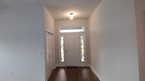 Ein Korridor mit einer weißen Tür, einem kleinen Fenster und einer Deckenleuchte.